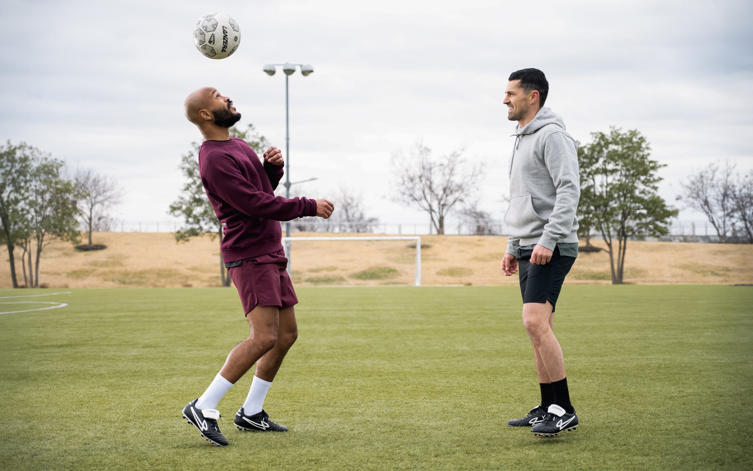Two footballers juggling on pitch wearing Lanzera Professionale black K-leather cleats.